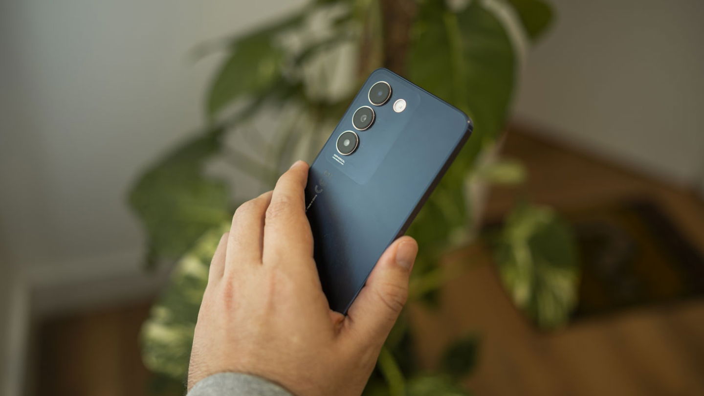 vivo V40 SE en el que se muestra la trasera en una mano con un fondo vegetal