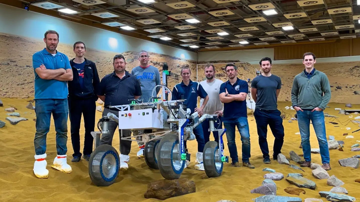 Investigadores del Glenn Research Center posan junto al rover, en un terreno que simula Marte