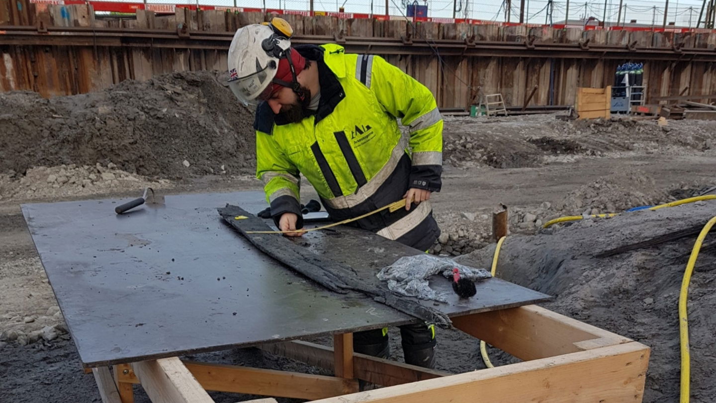 Un arqueólogo examina uno de los restos de madera hallados en el yacimiento de la ciudad de Varberg